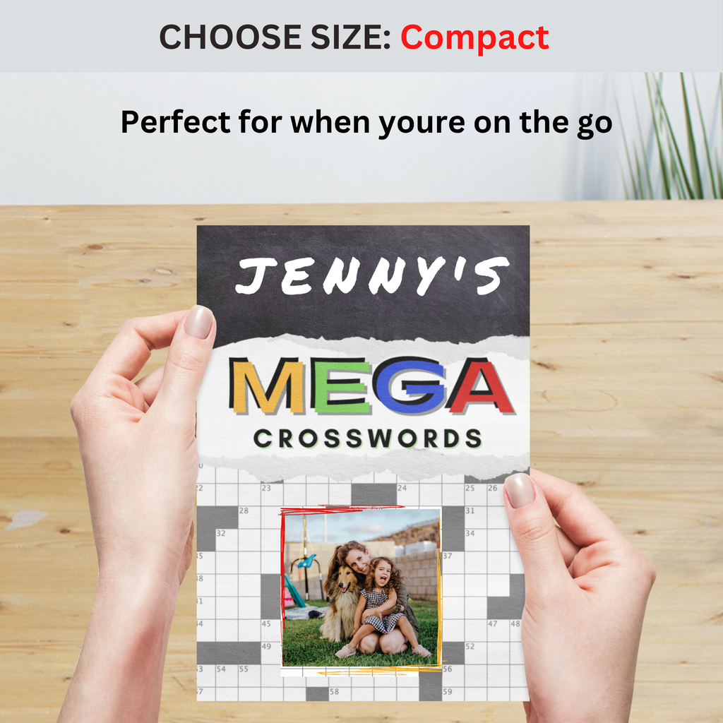 Hand holding a compact-sized 'Mega Crosswords' book on a wooden surface, featuring a personalized cover with a custom name and photo.