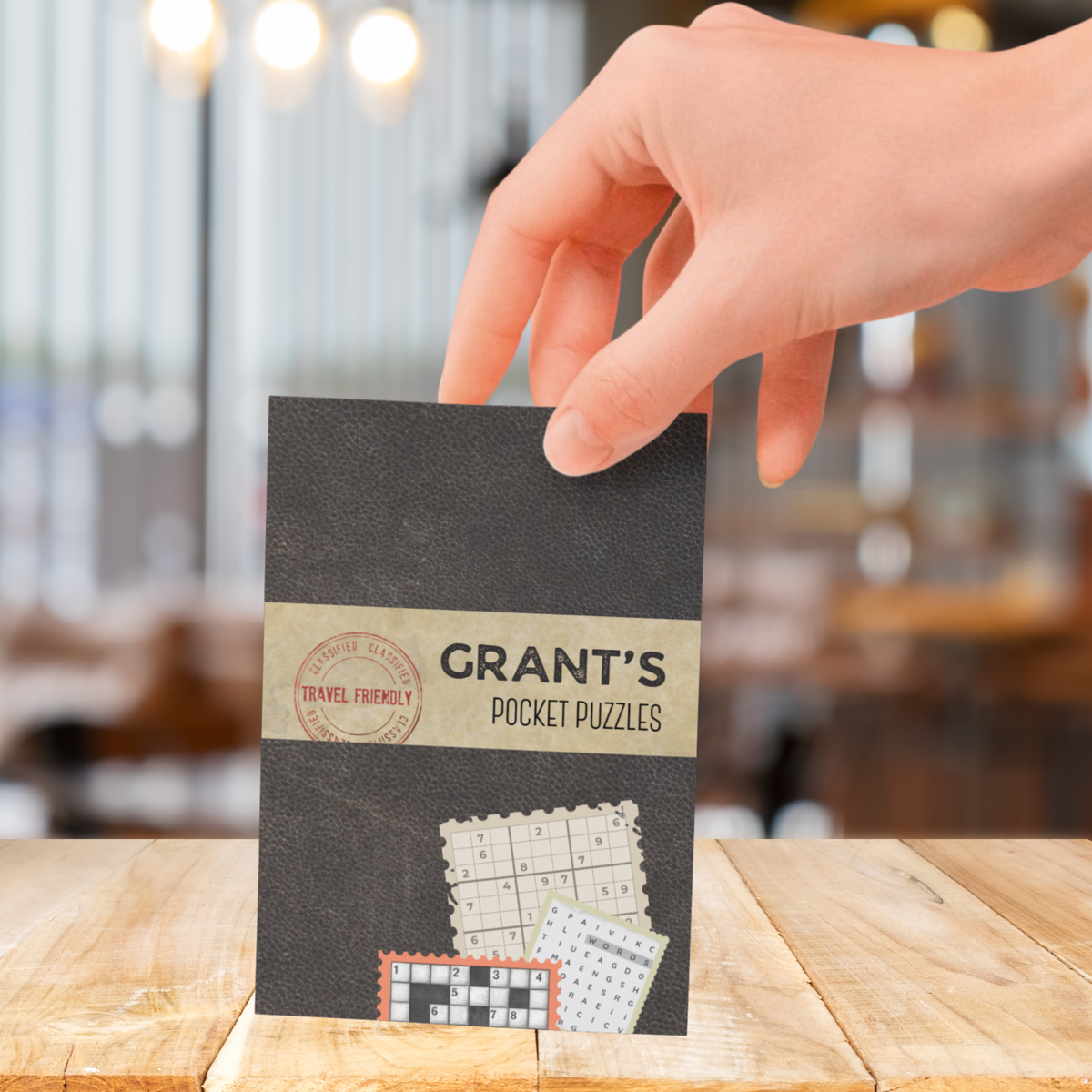 Hand holding a matte black pocket sized variety mix pocket puzzle book. 