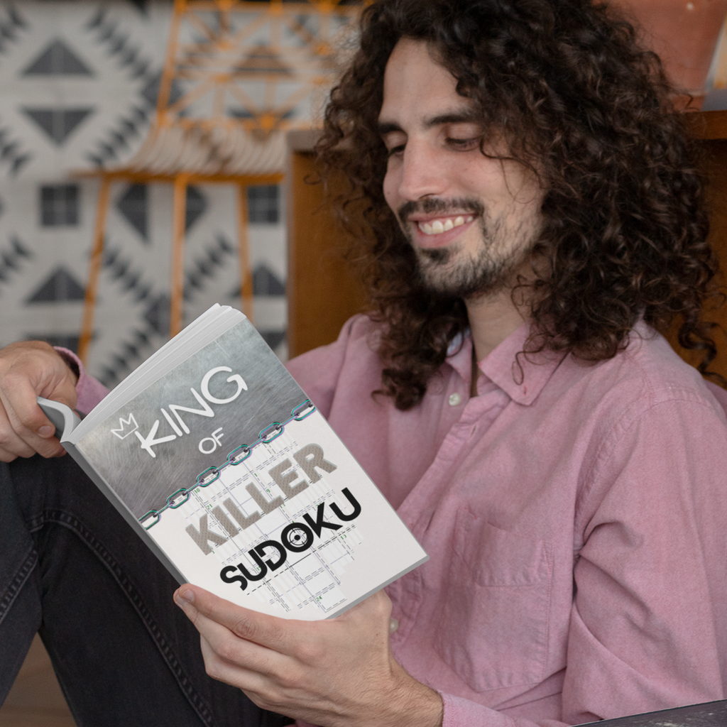 Man smiling while holding a kind of killer sudoku book  